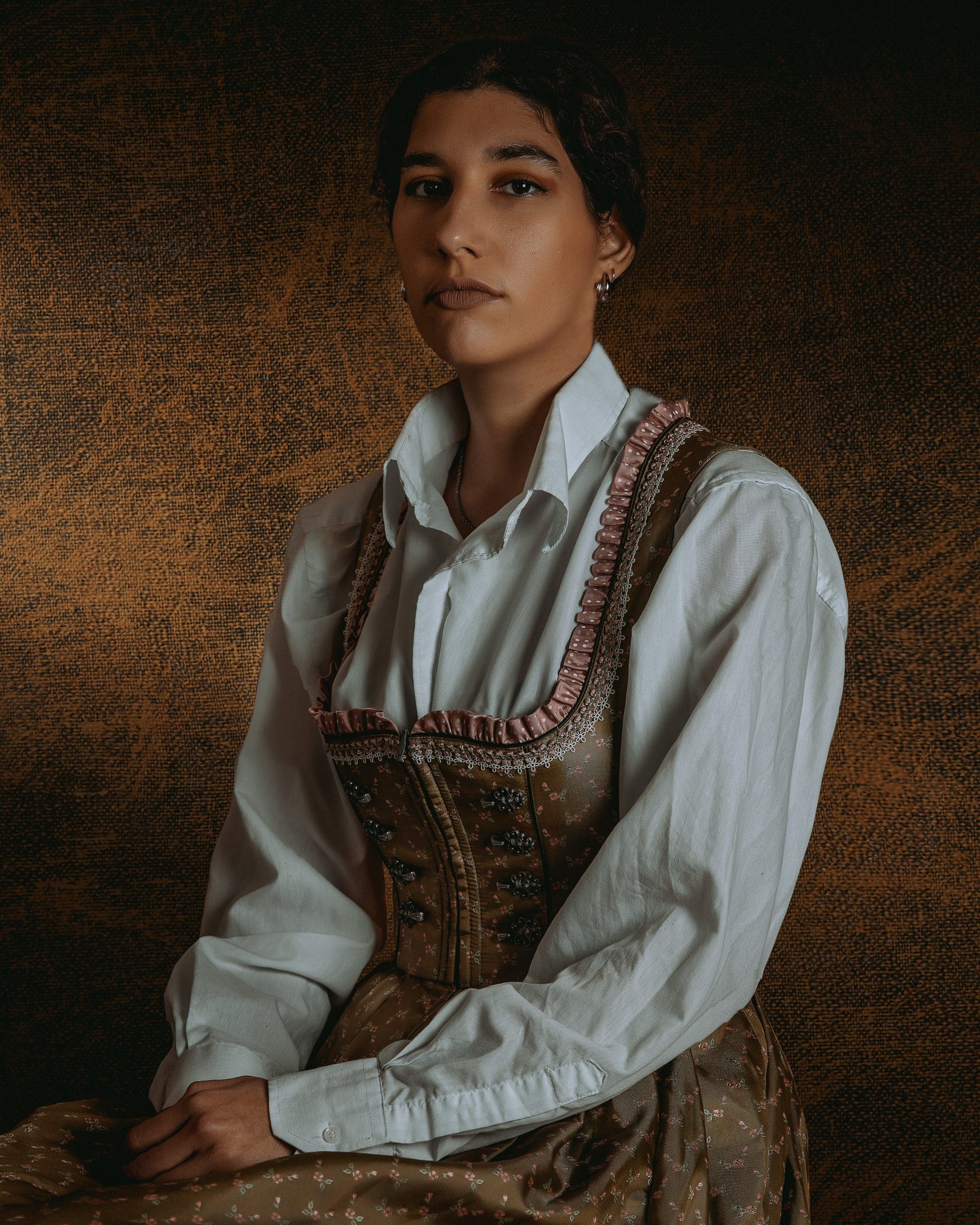 Φωτογραφία με κοπέλα που φοράει παραδοσιακό Γερμανικό φόρεμα σε καφέ αποχρώσεις, φωτογραφία σε studio στούντιο με φωτισμό φλας flash. Εμπνευσμένο πορτρέτο απο γάμους του 19ου αιώνα και παλαιότερους πίνακες ζωγραφικής Φωτογράφος γάμου Θεσσαλονίκη βάπτισης πορτρέτο . Το χρώμα του δέρματος την κάνει να μοιάζει με Ινδιάνα της Αμερικής .