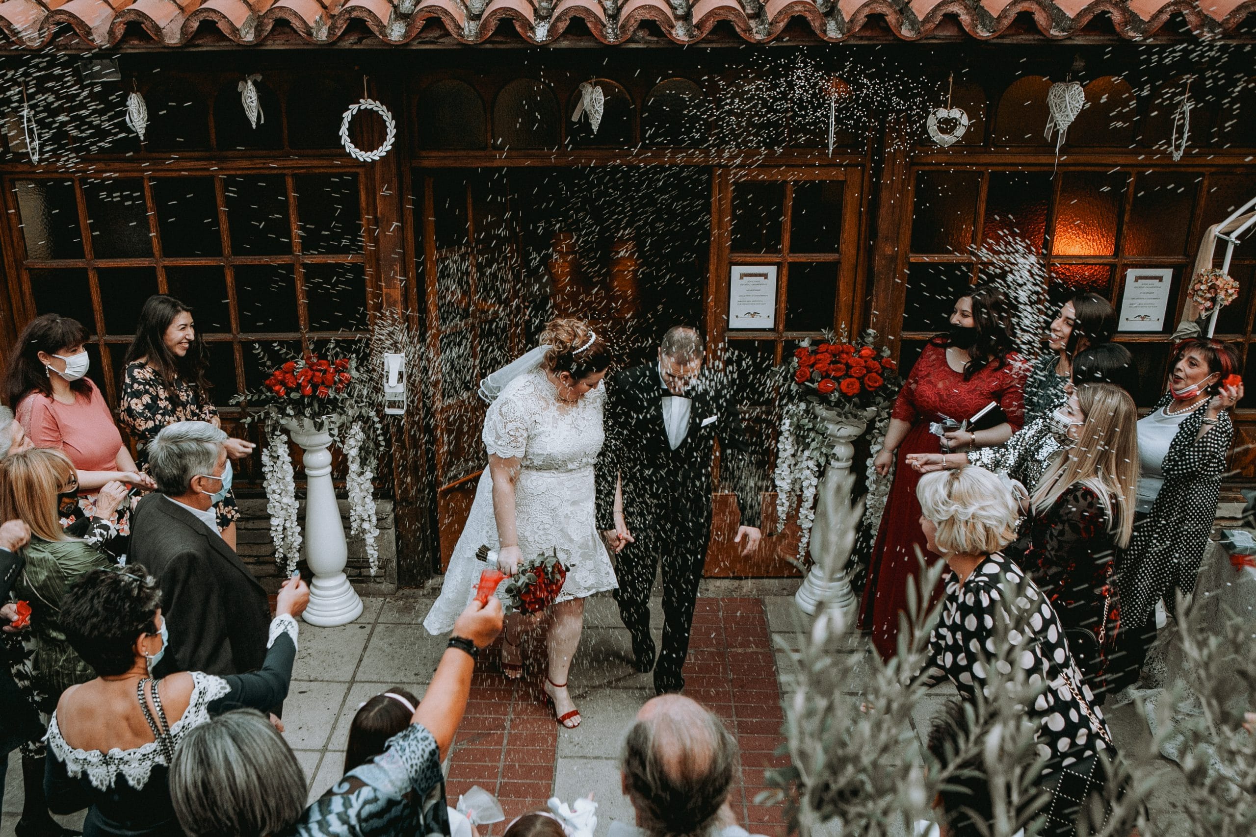 Φωτογραφία κατα την φωτογράφιση γάμου στην Θεσσαλονίκη, το ζευγάρι βγαίνει απο την εκκλησία και οι καλεσμένοι ρίχνουν ρύζι . Στην συγκεκριμένη φωτογραφία φαίνεται η χαρά της στιγμής . Ο γαμπρός φορά ενα μαυρο boss κοστούμι και η νύφη ενα ολόλευκο νυφικό με πέπλο και κόκκινα πέδιλα με φιάπα. Φωτογράφος Γιώργος Καρασαββίδης gkphotography
